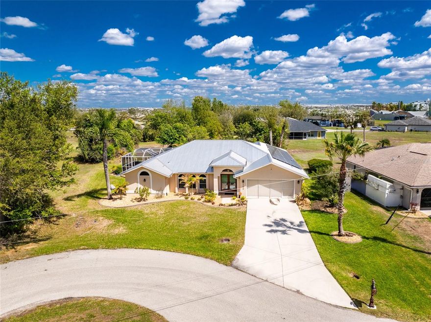 Located in the highly desirable, deed-restricted community of Deep Creek, this beautifully maintained home is tucked away at the end of a quiet cul-de-sac, offering both privacy and peace of mind. Enjoy the benefits of city water and sewer, along with the added advantage of being located outside of a flood zone. Inside, a split floor plan provides ideal separation for guests, while the centrally located kitchen is perfectly positioned for entertaining. The kitchen features granite countertops, a tiled backsplash, stainless steel appliances, and a breakfast bar, all complemented by ample counter space. Lower cabinets are equipped with convenient pull-out drawers for easy access, and a passthrough window to the lanai enhances indoor-outdoor living and makes entertaining a breeze. This home is loaded with upgrades including hurricane impact windows, a durable metal roof, and paid-off solar panels for energy efficiency. Plantation shutters add a touch of elegance throughout, and the home is being offered partially furnished for added convenience. The indoor laundry room adds everyday practicality. Step outside to your own private backyard oasis where the sun rises in the back, creating the perfect start to your day. Wake up at the crack of dawn with your cup of coffee as the sun comes up, then jump in and swim a few laps in your private pool. Surrounded by mature landscaping, decorative rock and curbing, and a fully irrigated yard fed by a private well, the setting is both lush and low maintenance. Conveniently located near I-75 at Exit 170, this home offers easy access for commuting while still enjoying a quiet neighborhood setting. Just a short 20-minute drive to Punta Gorda Airport, and close to shopping, restaurants, and medical facilities, making everyday living both easy and convenient.