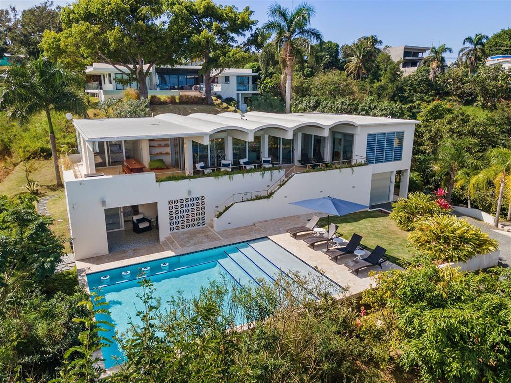 Contemporary Marvel with Sweeping Ocean Views – Designed by renowned New York architects Big Prototype, this magnificent single-family estate resides in Barrio Puntas - the most sought-after community in Rincon, known for spectacular ocean vistas and laidback elegance. This massive 6,300 square foot 5 bedroom, 4.5 bathroom home was designed to fully maximize it's premier hilltop location showcasing ocean views from nearly every room. From sunrise to sunset, the lush greenery, azure ocean, and fiery pinks of Rincon’s famed sunsets are your personal panoramic entertainment. Spread out over two floors, the barrel-vaulted ceiling brings a sense of amplitude and maximizes the open-plan living concept with an immense 30 ft x 40 ft great room. A surround sound system and a custom-built projection screen are hidden to allow for a movie theater quality experience, without sacrificing views or wall space. A separate TV area and offshoot of the living room provides even more space for lounging. Enjoy ocean views from the fully renovated kitchen featuring brand new LG appliances, an oversized island perfect to use as a breakfast bar and luxurious white quartz countertops throughout. The expansive terrace features a renovated outdoor kitchen and a large custom dining table providing multiple sizable spaces for entertaining Al Fresco. The main level has 3 bedrooms and 2 bathrooms off the principal living area, each with a sense of privacy and openness off the main terrace to appreciate the scenic views. On the second lower level, 2 bedrooms and 2 full bathrooms provide even more space and privacy. From the first level primary suite, an ensuite bathroom and private outdoor terrace provides the outmost peaceful retreat. Step out onto the charming colorful tile, inspired by 1960s spanish revival, and curl up with a book or dive directly into the oversized, heated saltwater infinity pool with swim-up bar. Celebrating its indoor-outdoor living concept, this palatial abode was meticulously designed as an entertainer’s dream. An outdoor shower and bathroom are thoughtfully placed off of the pool area. Large storage areas and a garage afford residents the ability to store every bit of gear needed to fully enjoy lounging at the beach and watersports. Relish the laid-back luxe ambiance that embodies the Rincon lifestyle - swimming, surfing, boating, hiking, fine dining, tranquility, nightlife, and the best sunsets in the Caribbean.
The home includes an eco-friendly greywater collection system that optimizes water collection as well as a full cistern and generator offering its residents all the modern comforts expected in a home of this stature.
Live or invest in the most exclusive sector of Rincon, located on the West Coast of Puerto Rico and known to be the surf capital of the Caribbean. A convenient 30 minute drive to the Aguadilla Rafael Hernandez Marin Airport, with direct daily flights from New York City, and other important city hubs make it an ideal destination in Puerto Rico.
Get informed about Puerto Rico's Act 60 Tax Incentive Program. Let us help you call this beautiful island HOME. Learn More: https://www.taxincentivespuertoricoinfo.com/