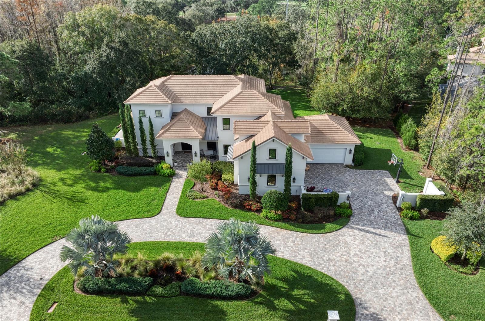 Experience the ultimate in luxury living in this magnificent residence located in Avila, Tampa Bay's premier guard-gated, golf, and country community. Built in 2019 by Campagna Homes, this custom-designed estate boasts 5,301 square feet of air-conditioned living space, 5 Bedrooms, 5 full and 1 Half Bathrooms, Bonus Room, Home Office, 4-car garage, and a breathtaking Swimming Pool and Spa. The meticulously landscaped grounds accentuate the architectural splendor of the home where you will also enjoy the unparalleled privacy on this 0.9 acre homesite. As you enter through the double front doors, you'll be captivated by the grandeur of the beautiful great room which includes 22-foot high ceilings, a coffered ceiling, Restoration Hardware Chandeliers, and a linear fireplace with a brick accent wall. The open floor plan seamlessly connects the dining room to the kitchen and the great room, creating an ideal setting for entertaining. The gourmet kitchen is a chef's dream, equipped with Thermador appliances, including a 6-burner gas range and double ovens. The kitchen island provides additional seating, and the adjoining kitchen dining room is perfect for informal gatherings. Adjacent to the kitchen is a guest bedroom with a Murphy bed which is currently used as a playroom and includes a full bathroom. The first-floor owner's suite serves as a sanctuary, featuring a spa-like bathroom and a spacious walk-in closet. The owner's bathroom boasts marble floors, a freestanding tub, frameless glass walk-in shower with a rain shower-head, marble tile accent walls, a water closet, and his/her vanities with granite countertops. The first floor is complete with a home office and a powder bathroom. Upstairs, you will find three ensuite bedrooms and a bonus room that can be utilized as an additional bedroom if needed. The outdoor living space is beyond compare and incudes a beautiful screened in swimming pool, spa, an outdoor kitchen, tongue & groove wood ceiling and temperature controlled fans. You will truly love your outdoor oasis with plenty of covered space to relax and dine. Immerse yourself in breathtaking luxury and privacy in this magnificent residence, while enjoying the security and privacy of living in Tampa Bay's premier golf and country club community, Avila.