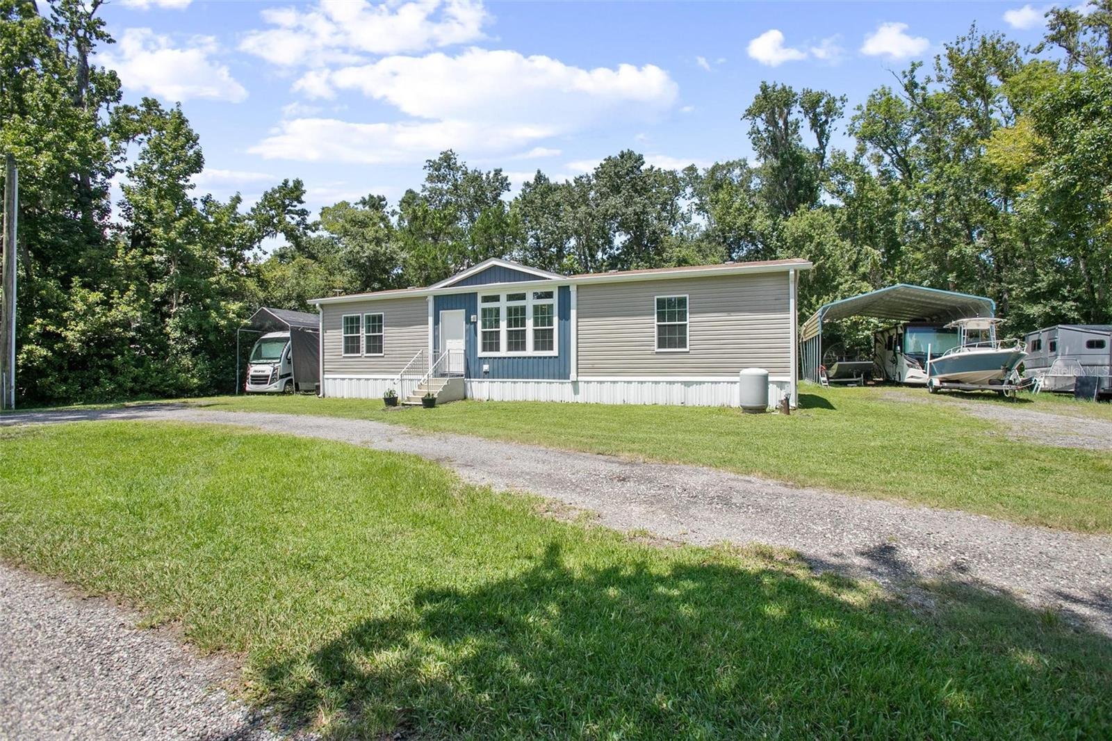 Discover the perfect blend of comfort and country charm in this private New Smyrna Beach retreat on 2.29 ACRES! This Jacobsen Homes model modular home, built in 2018 and first occupied in 2019, feels like new and offers a spacious layout designed for modern living. Inside, you’ll find a large open-concept living, family, and dining area, anchored by a chef’s kitchen with an oversized island and a walk-through pantry that’s as functional as it is impressive. The primary suite features a spa-style en-suite with a walk-in shower, ample storage, and plenty of space to unwind. Step outside to enjoy the expansive deck with a hot tub—the perfect spot for relaxation or entertaining.
The property also includes a pole barn (25’x35’x12’) with RV parking, a workshop (24’x35’x11’), and an additional storage covering (22’x20’), offering endless room for hobbies, tools, and equipment. Two fenced paddocks make it ideal for animals or those seeking a mini-farm agricultural lifestyle—all while being just minutes from the best of New Smyrna Beach, intercostal waters with public boat ramp, and the East Central Regional Rail Trail for even more outdoor fun!