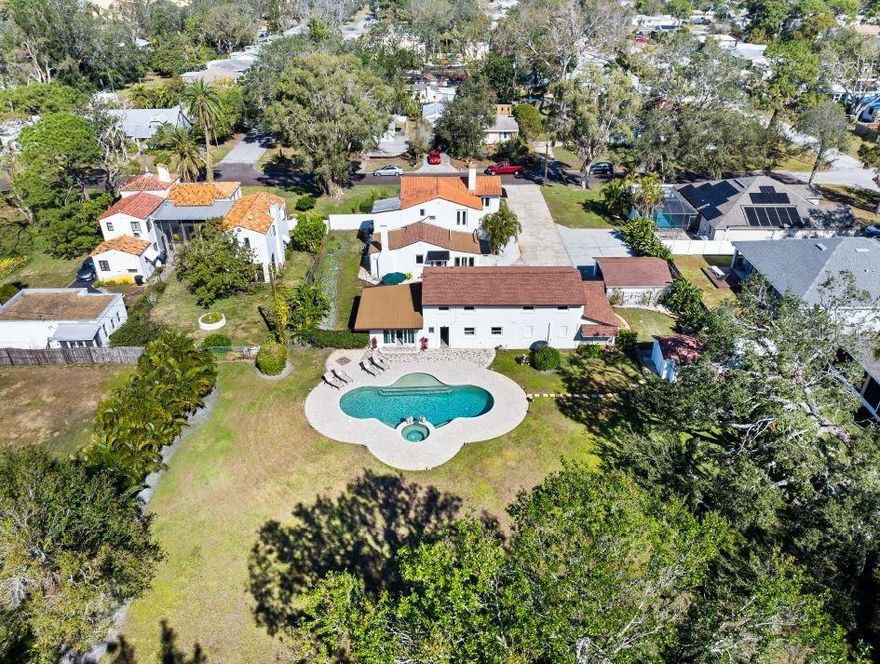 Perched approximately 19FT above sea level, your Dream Retreat Awaits. Discover this exquisite 1923 Spanish Mediterranean Revival pool home, gracefully nestled on nearly a full acre in the vibrant heart of Gulfport, Florida. From the moment you step through the front door, you're greeted by timeless elegance and authentic architectural details. The formal living room exudes warmth and character, featuring a grand gas fireplace, original wood floors, rich wooden ceiling beams, and an abundance of natural light streaming through expansive windows. Through classic French doors, escape to a charming library adorned with original Cuban tile flooring and direct access to the outdoors — the perfect setting for quiet reading or afternoon reflection. A graceful archway leads to the formal dining room, ideal for hosting memorable dinners. The spacious family room is lined with windows offering tranquil views of the garden and historic carriage house, creating a seamless blend between indoor luxury and outdoor serenity. On the first floor, an inviting en-suite bedroom impresses with a dramatic arched entry and a private stone fireplace. The gourmet kitchen is a chef’s delight, boasting soaring ceilings, exquisite heart-of-pine floors, a six-burner gas range, stainless steel appliances, and a unique step-down walk-in pantry for abundant storage. A charming half bath completes the main floor. Upstairs, the main en-suite bedroom offers a private balcony with period details — a serene perch to enjoy the Gulf breeze. The third bedroom is currently styled as a sophisticated home office. A luxurious guest bath features a marble walk-in shower, marbled floors, and a classic claw-foot tub. The separate Carriage House offers exceptional versatility. Its first floor hosts a private guest en-suite with sliding doors opening to the heated saltwater pool and lush grounds, as well as a dedicated laundry room. Upstairs, a spacious, light-filled open room currently serves as a gym, complete with its own marble bathroom. Ample parking includes a 2-car garage, an additional 1-car carport, a detached 2-car carport, and a large driveway pad. The fully fenced backyard, with rear lane access, is an oasis of privacy and beauty. Located outside of the flood zone and just minutes from the vibrant offerings of Gulfport, St. Petersburg, Tampa, and Sarasota — this exceptional estate blends timeless charm with modern comfort.