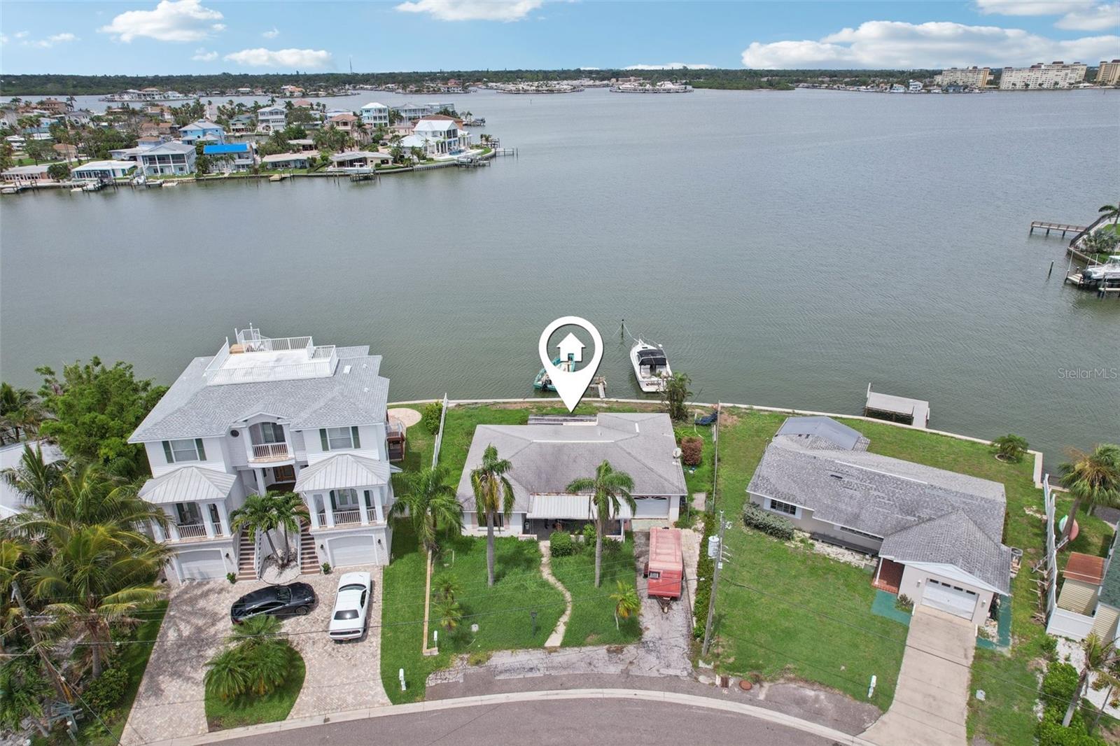This Redington Beach home, nestled on a point lot with 87 feet of waterfrontage across nearly 8,000 square feet, offers unobstructed, breathtaking views of Boca Ciega Bay. Though significantly impacted by the 2024 hurricanes and being sold as is, its prime location is undeniable. Situated on picturesque Redington Drive, just four blocks from the beach, this property boasts yacht and sailboat parking availability. The seawall is fortified with a concrete cap, ensuring durability. Both sides of the property are securely gated and fenced through the backyard, with "wings" extending over the seawall, providing both privacy and protection. The expansive backyard also presents an ideal setting for an in-ground pool, allowing you to create your own waterfront oasis. Beyond the property's allure, Redington Beach enhances the coastal lifestyle with exclusive "residents only" Gulf-front beach access. This private amenity includes convenient parking, an outdoor shower, and comfortable seating, all for the enjoyment of its residents. The city further complements this vibrant community with access to basketball and shuffleboard courts, and a playground. This is an unparalleled opportunity to bring your vision to life and own a piece of paradise in one of the most desirable areas of the beaches.