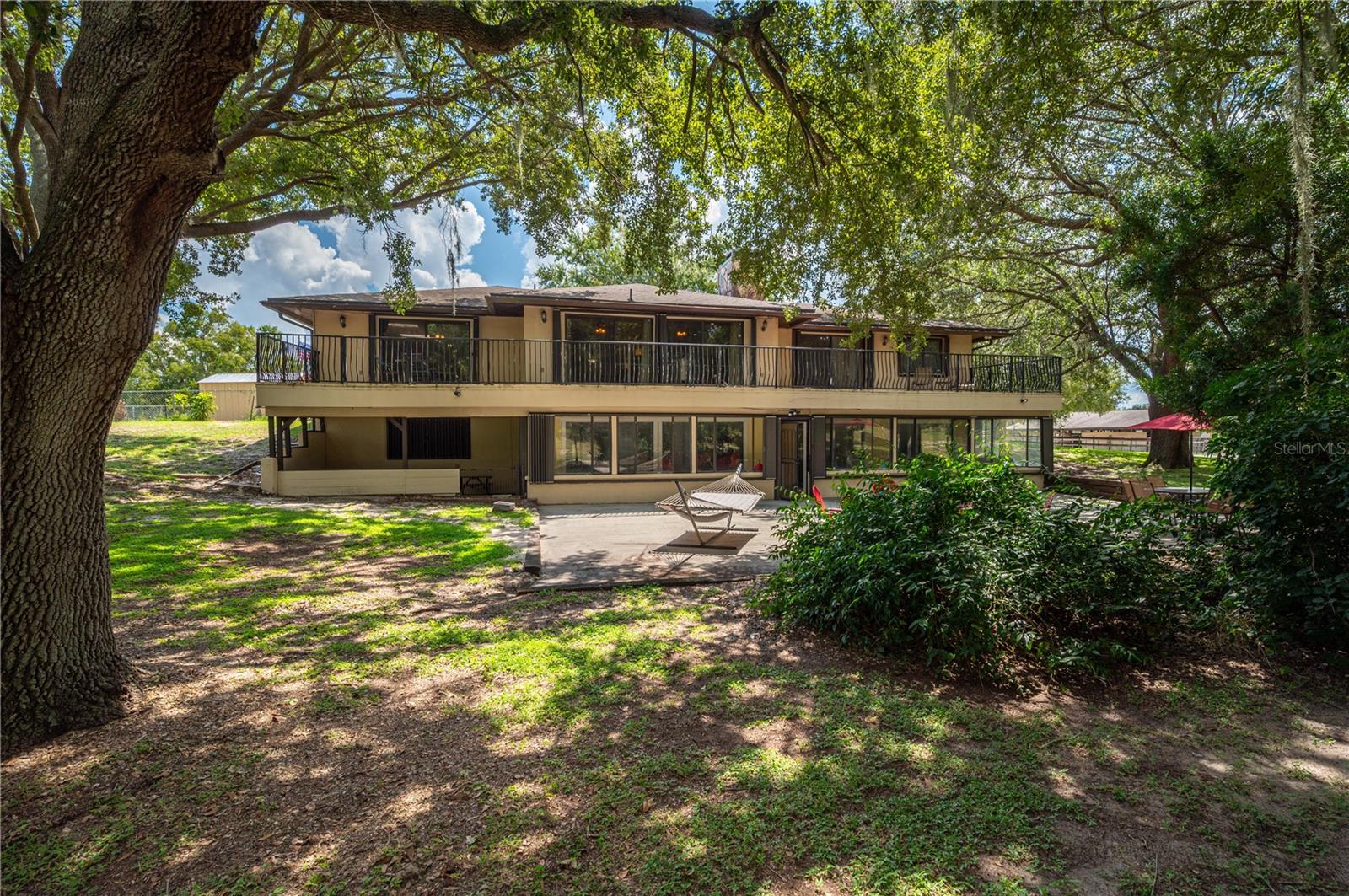 There's more to this home than meets the eye! Bring your horses and enjoy the ultimate equestrian lifestyle with this 4-bedroom, 3-bathroom home on 8.26 fully fenced acres in the Blue Jordan neighborhood of Frostproof, Florida. This property is designed for horse enthusiasts, featuring a 6-stall barn complete with paddock areas, tack room, feed room, and additional stalls for versatile use. A large, covered metal shed/barn provides plenty of space for hay storage and trailer parking, while a round pen is perfect for training. The entire property is fenced and cross-fenced, secured by an entry gate and a cement driveway leading to both the residence and stable area. This uniquely designed home features a walk out basement providing a wonderful connection to the outdoors! Inside, the main level welcomes you with a spacious living room centered around a wood-burning fireplace. The open-concept kitchen boasts wood cabinetry, granite countertops, stainless steel appliances, and an island with bar seating. Conveniently located on the main floor are the laundry room, guest bath, and a giant primary suite offering a luxurious bath with double vanity, tiled shower, jetted tub, and bidet. Downstairs, enjoy a cozy family room with a second fireplace and wet bar area. Perfect for entertaining! There are two additional bedrooms with a Jack-and-Jill bath, plus a fourth bedroom currently being used as a home office/library. Nearly every room in the home provides access to the expansive back balcony and porch/patio, offering panoramic views of the oak-shaded backyard and pasture. Additional features include an oversized two-car garage (garage door and opener replaced 2024) with cabinet storage, two newer AC units with extended warranties and hurricane shutters. Roof replaced in 2020! This property combines a generous sized home with all the amenities needed for serious equestrian living! Schedule your private showing today!