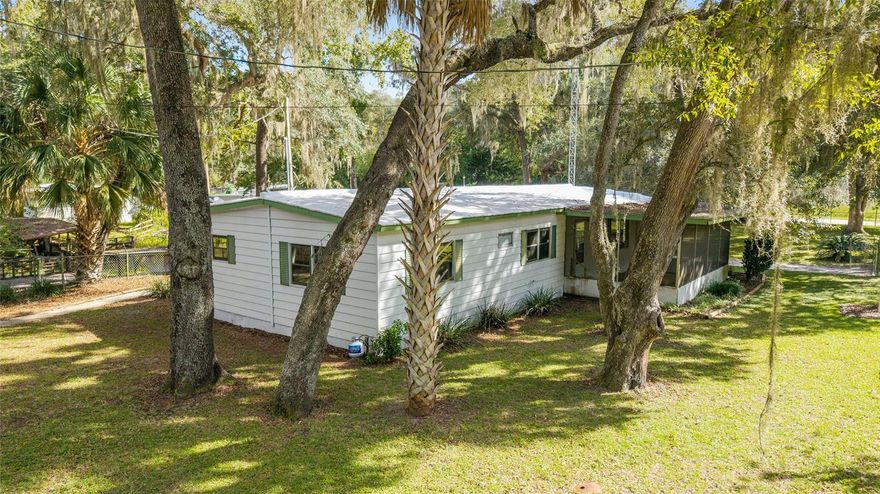 Charming mobile home nestled among majestic oaks on a meticulously landscaped oversized lot, .88 Acres. This well-maintained residence features 3 bedrooms, 2 bathrooms, including a spacious master bathroom, and an extended carport, perfect for outdoor entertaining. Enjoy a serene canal leading to Orange Lake, complete with a deck and 2 boathouses equipped with functional electric. Spanning three combined lots (home on two), this property boasts a newer 4-year-old AC unit, a 1-year-old well and water pump, a fenced yard, and a convenient workshop and shed. A perfect blend of comfort and waterfront living!