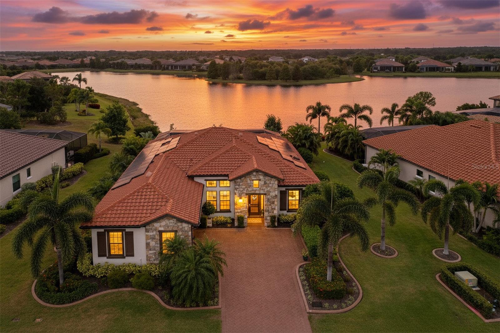 Beautifully positioned on a premier homesite in Country Club East, this highly upgraded home captures tranquil lake and preserve views and blends thoughtful design with energy-efficient living. Freshly painted inside and out, the residence is outfitted with hurricane impact-rated windows and doors, solar panels, and dual Tesla Power walls—keeping electric bills remarkably low while providing peace of mind with uninterrupted power in any weather. The open layout is warm and inviting, featuring a kitchen that offers style and function with quartz countertops, a large center island, designer lighting, walk-in pantry, coffee bar, gas cooktop, and stainless appliances, while the great room showcases a stacked-stone accent wall with an electric fireplace. The owner’s retreat is a private sanctuary with custom wood wall and ceiling details, a custom-built closet, and a spa-like en suite with quartz counters, dual sinks, a frameless walk-in shower, linen closet, and private water closet. Three guest bedrooms, (or two guest beds and an office,) and three full baths provide flexible living. Outside, a saltwater pool and spa, gas fire pit, outdoor kitchen, clear-view screening create the perfect setting for relaxing or entertaining—enhanced by motorized hurricane screens, electric lighted awning and lanai lighting. Additional highlights include whole house reverse osmosis water system, landscape lighting, designer interior lighting, a cypress wood ceiling in the dining room, a spacious garage with EV outlet, tankless water heater, storage racks and cabinets - all within the privacy of a gated community offering resort-style amenities and optional Lakewood Ranch Golf and Country Club membership. Lakewood Ranch is the number one best-selling, multigenerational community in the country and located near world-class shopping, dining, entertainment of Lakewood Main Street, University Town Center, downtown Sarasota and is minutes to I-75, beaches, great schools and medical facilities.
