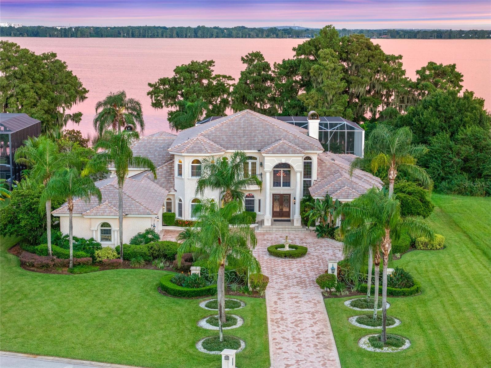 Discover ultimate luxury lakeside living with this remarkable 4-bedroom, 5.5-bath estate in the exclusive, gated community of Heron Cay. Perfectly situated on 1.04 lush acres with 145 feet of private shoreline on Lake Eloise—part of Central Florida’s iconic *Chain of Lakes*, this home offers a rare blend of timeless elegance, exceptional comfort, and breathtaking views.
Upon entering, you're welcomed into a grand living room where floor-to-ceiling windows frame panoramic lake views lake and fill the space with natural light. A cozy gas fireplace adds warmth, while the adjacent formal dining room is ideal for intimate dinners or large celebrations.
The left wing of the home features a gourmet kitchen with high-end finishes, multiple dining spaces, and a convenient pass-through window to the pool, perfect for effortless entertaining. The expansive great room includes a second gas fireplace, an upscale wet bar, and inviting lounge areas. This side of the home also offers a private office, half bath, and a guest bedroom with en-suite bath.
The right wing features two spacious bedrooms with en-suite baths, a large laundry room, and a versatile bonus/game room with sliding doors to the pool and its own poolside-access bathroom, ideal for guests or entertaining.
Upstairs, enjoy a built-in library, a private fitness area with floor-to-ceiling mirrored walls, and a lavish primary suite featuring a wet bar, relaxing sitting area, two oversized walk-in closets, and a private balcony with stunning lake and infinity pool views. The spa-like master bath includes a jetted tub, a multi-head shower, bidet, and modern conveniences like built-in drawer outlets for a sleek, clutter-free look.
The outdoor living space is designed for luxury and leisure, complete with a summer kitchen, full bar, hot tub, and multiple seating areas with unrivaled lakefront views. As a bonus, enjoy front-row seats to LEGOLAND’s fireworks right from your own backyard oasis.
Smart home features include advanced Control4 automation for lighting, music capability in every room, intercom, and front-door communication, plus a full security system for peace of mind. Additional highlights include high-mounted holiday lighting outlets and built-in night lights that softly illuminate your home each evening.
Living on the Chain of Lakes offers a one-of-a-kind waterfront lifestyle, with endless opportunities for boating, waterskiing, lakeside dining, and fishing across 20+ connected lakes. Ideally located between Tampa and Orlando, you’ll enjoy quick access to airports, premier medical facilities, shopping, dining, theme parks, and more.
Don’t miss this opportunity to own a true lakeside masterpiece. Schedule your private showing today and experience the best of Florida living!