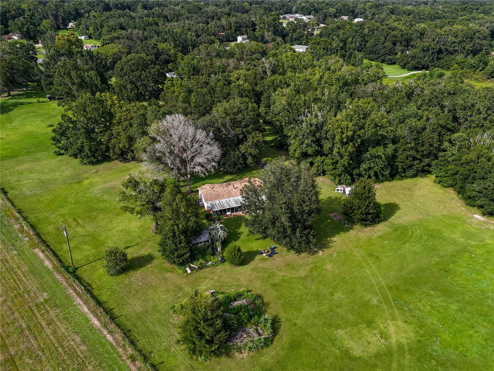 This charming Brooksville home boasts 3 bedrooms, 2 bathrooms, and 1512 square feet in a thoughtful open floor plan with a split bedroom design. Having been newly renovated in a farmhouse-style interior and featuring a gas or wood burning fireplace in the living area, you'll fall in love with this home. The master suite features a walk-in closet, sliding barn doors, and a modern bathroom complete with a relaxing soaker tub and a sleek walk-in shower design. A large rear porch overlooks 10 acres of gently rolling agricultural land, offering scenic views and frequent wildlife sightings. The home is tucked back from the road, with a front solar powered gate, ranch-style fencing, and a private asphalt road leading to the residence. This property is a rare find with the desirable acreage being located in a sought-after quiet Brooksville country neighborhood off Croom Road.
This property is just 5 minutes from historic downtown Brooksville with its coffee shops, restaurants, bakeries, and popular boutiques. Downtown Tampa is under an hour away via US Hwy 41, the Suncoast Parkway, or I-75, offering access to Tampa International Airport, major shopping, and job opportunities. Orlando is only 1.5 hours east, while the Gulf Coast, Weeki Wachee, Crystal River, and Homosassa River are still within driving distance for fishing and water activities, all without the concern of coastal flooding.
RARE FIND.