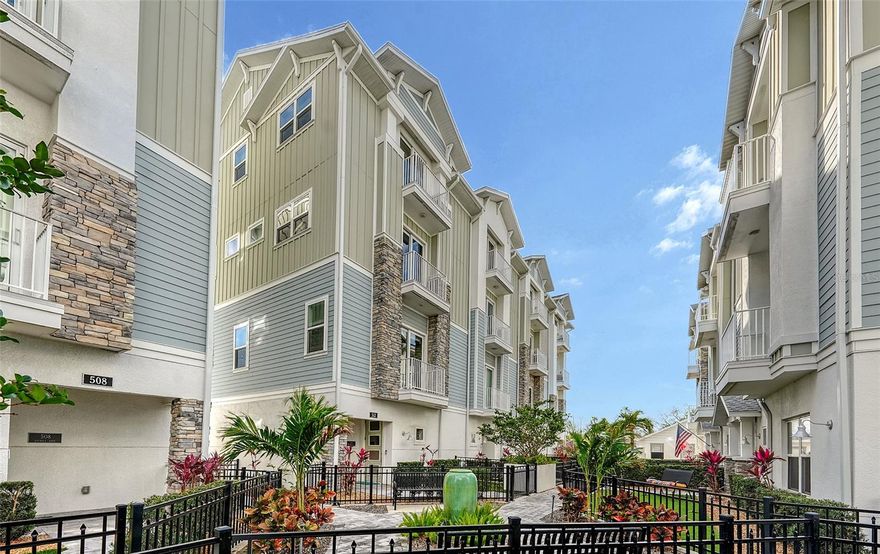 Price Improvement! Discover an incredible opportunity to own a stunning townhouse in the heart of Sarasota’s historic Laurel Park District, now offering exceptional value and a brand-new air conditioning system for added comfort and peace of mind. Step through the gated, low-maintenance front yard overlooking the community fountain and enter a welcoming foyer, where a private elevator provides effortless access to every level of the home. Designed for both comfort and entertaining, the expansive living area features an open-concept kitchen that flows seamlessly into the dining and living spaces. The chef-inspired kitchen showcases stainless steel appliances, solid stone countertops, and a designer tile backsplash. A conveniently located half bath completes the main living level. The third level is dedicated to the owner’s primary suite, featuring a spa-like bathroom with a large walk-in shower, double vanity with generous counter and cabinet space, elegant tile work, and a custom walk-in closet. Just steps away, a well-appointed laundry area includes a washer, dryer, and large utility sink. Adjacent to the primary suite is a versatile space ideal for a home office, TV lounge, library, or play area. The top level offers two additional en-suite bedrooms, providing comfort and privacy for guests or family. Engineered hardwood floors run throughout the home, complemented by tile in all bathrooms and a neutral color palette that suits a variety of styles. As an end unit, the residence is filled with natural light from additional windows, enhanced by custom wood and fabric blinds. Each level features two balconies, creating a seamless connection between indoor and outdoor living. This exceptional downtown residence also includes a private two-car garage, a large storage closet, and low HOA fees, making it an ideal low-maintenance lifestyle option. Enjoy the best of city living with a walkable location close to Sarasota’s vibrant Main Street, Bayfront, art galleries, dining, boutiques, grocery stores, parks, and the Legacy Trail. The home is also conveniently located near Sarasota’s renowned beaches, including Siesta Key and Lido Beach. All offers are welcome. Don’t miss this opportunity to experience downtown Sarasota living at its finest.