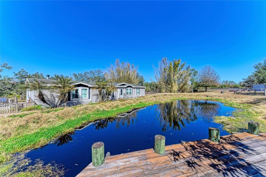 WELCOME TO TWO-HOMES ON 5 ACRES of country living in Beautiful & Peaceful Myakka!  With NO HOA or Deed Restrictions- offering privacy, space, and comfort it is perfect for livestock with luscious pastures, or an investment property.  The main Modular home overlooks a pond that will not flood, because of pipes allowing water up to a certain level and fully stocked with fish. 
The home has an open-concept design ideal for both daily living and entertaining. The home offers 3 bedrooms, 3 bathrooms, a den,  with the primary bedroom having a spacious walk-in closet and nice size rooms throughout. An office is conveniently located near the primary suite, and a cozy wood-burning fireplace anchors the dining area. The kitchen has a window over the sink looking out to the vast property, with a dishwasher hook-up.  The laundry room has a washer/dryer powered by propane tank with extra storage and the rest of the home runs on electricity.  There are 2-wells and 2-septic tanks on the property.
Outdoor living is equally impressive. Enjoy morning coffee on the screened-in back porch overlooking the lush acreage, or unwind by the firepit at night.  
A separate second Mother-in-law suite home on the property is over carports, featuring 2 bedrooms, 1 bathroom, a full kitchen, front-load washer and dryer, and a beautiful wood-burning fireplace in the living room for cold nights. Below the suite is a 2-car carport with a full storage room, providing both convenience and functionality.
This property is exceptionally well-equipped for toys, vehicles, and equipment, RV electric hookup, full size shed, barn and a short walk to the creek with a beach. There is ample room to add stables, making this property ideal for horses, cattle, or other livestock.   Located just a short drive from Lakewood Ranch and Sarasota, this gated property blends peaceful rural living with everyday convenience.
With this estate-sized parcel property perfect for investors to rent out or expand on original structuress with unmatched flexibility—it is ready to enjoy today.