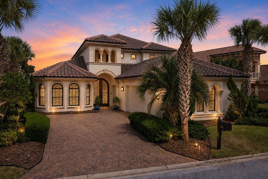 Welcome to an extraordinary Arthur Rutenberg luxury residence on coveted Kingfisher Lane within the exclusive gated community of Ocean Hammock — a vibrant and welcoming street known for its friendly neighbors, festive block parties, and strong sense of community. Perfectly positioned on a serene lakefront homesite overlooking the golf course and just moments from the Atlantic Ocean, this impeccably designed home offers a rare blend of elegance, comfort, practicality, and coastal sophistication.

From the moment you arrive, the striking Mediterranean-inspired architecture, paver driveway, and stunning custom cast-iron double entry doors create a breathtaking first impression. Inside, soaring ceilings, rich wood flooring, dramatic cast-iron staircase detailing, coffered ceilings, and abundant natural light elevate every space with timeless luxury and architectural character.

Thoughtfully designed for both everyday living and effortless entertaining, the expansive floor plan offers exceptional functionality alongside refined aesthetics. The first-floor primary suite provides a peaceful private retreat, while the conveniently located first-floor study with double doors creates the perfect home office, library, or flex space just off the main living area.

The grand great room flows seamlessly into the gourmet kitchen, beautifully appointed with custom cabinetry, granite countertops, premium stainless-steel appliances, an oversized breakfast bar, and center island designed for gathering with family and guests. Extensive storage throughout the home — including large storage closets and cleverly utilized attic space within the roof trellis design — reflects the careful attention given not only to beauty, but to livability and practicality.

Upstairs, the home is perfectly designed for hosting family and guests with spacious guest suites featuring ensuite bathrooms, a versatile loft living area, and a private screened balcony capturing gorgeous lake and golf course views along with refreshing ocean breezes drifting in from the nearby Atlantic.

The primary suite is a luxurious sanctuary of its own, featuring warm wood flooring, elegant tray ceilings with natural textures, abundant natural light, and a serene sitting area perfect for morning coffee or quiet evenings. The spa-inspired primary bath offers dual vanities, granite countertops, a soaking tub, walk-in shower, and an atmosphere designed for relaxation and retreat.

Step outside to the spectacular screened lanai where the true magic of coastal living unfolds. Enjoy peaceful evenings soaking in the spa while listening to the distant sound of the Atlantic Ocean, feeling cool ocean breezes, and watching the sky transform with breathtaking sunset colors before the moon rises over the lake. The tranquil golf and lagoon setting attracts an abundance of natural wildlife, creating a constantly changing backdrop of tropical birds, turtles, and even playful otters gliding through the water.

This exceptional Kingfisher Lane residence offers the ultimate combination of luxury, warmth, functionality, and lifestyle within one of Palm Coast’s most sought-after coastal communities.