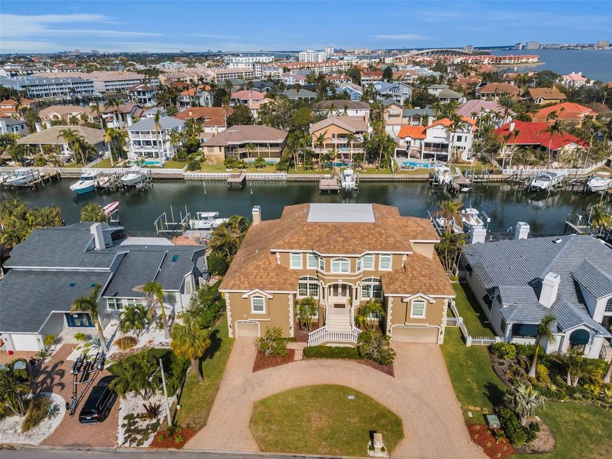 THIS IMPRESSIVE 6 BEDROOM, 4 ½ BATH COASTAL ESTATE OFFERS 9512 SQFT UNDER ROOF AND BEAUTIFUL PROTECTED BOATING WATER WITH RAPID ACCESS TO THE GULF OF MEXICO. A grand, pavered circular driveway introduces a majestic and inviting covered entry. Step through to the wonderful open foyer and superb living room with towering 23ft-high ceilings and lavish custom wood/granite multi-level wet bar with wine/beverage chilling center. This exceptional luxury waterfront home features remarkable tray & custom layered ceilings, extensive built-ins/crown trimwork, elegant 24-inch polished marble tile floors, and 12ft-high ceilings in the 1st living level. An exquisite formal dining contains a beautiful built-in serving buffet with matching corner curio cabinets. The brilliant gourmet kitchen boasts splendid ogee-edge granite counters, exceptional custom wood cabinetry, beautiful designer tile backsplash, a rich island prep center, built-on refrigeration, Wolf gas cooking, and a large multi-level breakfast bar. Spacious family room enjoys a built-in entertainment center with fireplace, overlooks the water, and opens to the main 37ft-wide, 450sqft waterfront balcony – perfect for family and friends. Retire to the inspiring owner’s suite with 2 walk-in closet systems and a large waterfront sitting area that includes a built-in mini office and terrific morning bar with beverage center. Resplendent owner’s bath is a pampering retreat, with custom cabinetry, granite surfaces, 2 generous vanities, a dedicated cosmetics center, a jetted spa tub encased in granite/wood, and a dazzling walk-in marble rainshower with body sprays. Additional 1st level bedroom suite has waterviews and a plush full bath. Upstairs, discover 4 well-sized bedrooms, 2 of which overlook the water and share a 150sqft deck with commanding views of the waterfront. Upper level provides a built-in lofted lounging area and fabulous interior views of the home. Step out to the 1125sqft covered lower level deck overlooking the pool/waterfront. This huge deck has 4 distinct seating areas, including a substantial multi-level granite bar & dining center with outdoor kitchen, SS gas cooking and custom brick oven. Oversized lounging deck encircles the pool/spa. Superior construction, massive garage, excellent laundry facility, composite dual entry boat dock with lift, and many, many extras. An incredible waterfront value in a terrific boating community! Buyer to verify all dimensions. Flood insurance is $1287 per year and assumable.