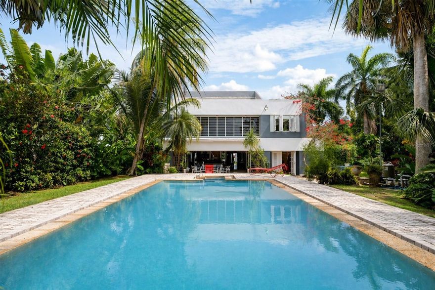 Welcome to this stunning architectural jewel in Garden Hills, a unique masterpiece designed by a renowned architect showcasing a harmonious blend of urban elegance and modern functionality, offering an unparalleled retreat just moments from the city and a few steps to the Caparra Country Club. Situated in a very private dead end street of Garden Hills Norte in a gated community, this is one of THE most exclusive coveted neighborhoods in Guaynabo and the San Juan metro area. This thoughtfully designed home features an open-concept floor plan perfectly integrating the ample dining area to the majestic Great Room with its soaring double height cathedral ceilings, all seamlessly flowing to the 3 terraces surrounding it in every corner. The perfect flow between the indoor and outdoor living areas connects all three terraces to the 2 tranquil koi ponds and the striking infinity pool in the center, providing a peaceful and serene oasis, yet also ideal for hosting and entertaining large gatherings.  The home also boasts 3 bedrooms all with baths and a fourth bonus, or caretaker’s bedroom also with a bath, a family room, a powder room and an office with a separate entrance overlooking the scenic gardens. The master bedroom has its own private terrace with an outdoor pool/spa also overlooking the lush beautiful gardens. The chef’s kitchen combines sleek finishes with functionality and opens to another terrace and small pond, making it ideal for intimate gatherings. The office features custom built-ins and faces another terrace with an oriental style pond filled with water lilies, adding a unique peaceful and inspiring work area to the room. All is complemented with more luxurious details such as abundant natural light, fresco paintings, a 1000 bottle wine cellar, stone floors, an elevator, stained glass windows, 2 car garage, a generator and a cistern.  
This contemporary sanctuary is only 12 minutes from San Juan and right next to some of the best schools, great restaurants, superb shopping venues and excellent sport facilities, combining suburban and city living at its best. Also available for RENT.