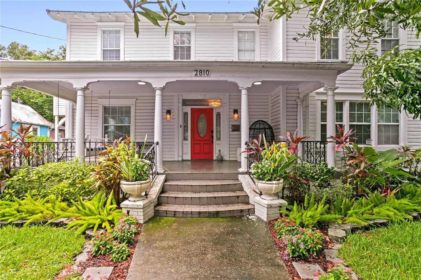 Located in the heart of the Ybor City National Historic Landmark District, this rare and character-rich Folk Victorian-style home offers a beautiful blend of historic charm, modern amenities, and income-producing potential on a lush, oversized 0.22-acre lot shaded by mature live oak trees and enclosed by a white picket fence. The estate includes a total of 3,720 sq ft, featuring a 3,030 sq ft main home and a fully permitted 690 sq ft detached ADU built in 2019—ideal for multigenerational living, rental income, or guest accommodations.
With its welcoming front porch with swing and detailed wood-turned porch columns, the home reflects classic 1920's era design—simplified yet elegant, with just the right touch of decorative detail. The 4-bedroom, 2.5-bath main residence pairs architectural character with an open-concept layout, built-in storage in the foyer, a separate first-floor den with French doors, first floor bedroom, and a striking wood-turned staircase. The main floor features high ceilings with recessed lighting, creating a bright and airy living and dining space. The updated kitchen includes new tile flooring, stainless steel appliances, granite countertops, a pantry closet, and a secondary prep sink. Hardwood flooring runs throughout the primary living areas and bedrooms, providing warmth and continuity. The primary suite offers dual closets, dual vanities, and a separate water closet. Two additional bedrooms, full bath, and laundry room are located on the second floor. Additional upgrades include fresh interior paint and a newer metal roof. Enjoy multiple outdoor living areas, including a deck off the rear of the home and a second-story rooftop terrace spanning nearly 600 sq ft, ideal for entertaining or relaxing while overlooking the private backyard sanctuary. The beautifully landscaped yard features mature tropical plantings, a tranquil pond, an oversized storage shed with attic space, covered carport, and even a chicken coop—a true private retreat just minutes from the city. The detached ADU includes a private entrance, separate laundry area, two bedrooms, a main living space, a full bath, and a kitchen with stainless steel appliances and low maintenance vinyl flooring. Clean 4-point inspections are on file for both structures, offering peace of mind. Perfectly located just blocks from historic Ybor City and minutes from Downtown Tampa, Channelside, Water Street, and the transformational Gas Worx and Ybor Harbor developments, this home is part of Tampa’s most exciting urban renaissance. These projects are stitching together the city’s most iconic districts with walkable streets, green space, waterfront access, and dynamic residential growth. Whether you're looking for a charming primary residence, a multi-use property, or a future-focused investment, 2810 N 10th St offers timeless architecture, modern comfort, and unbeatable location—all in one exceptional offering.