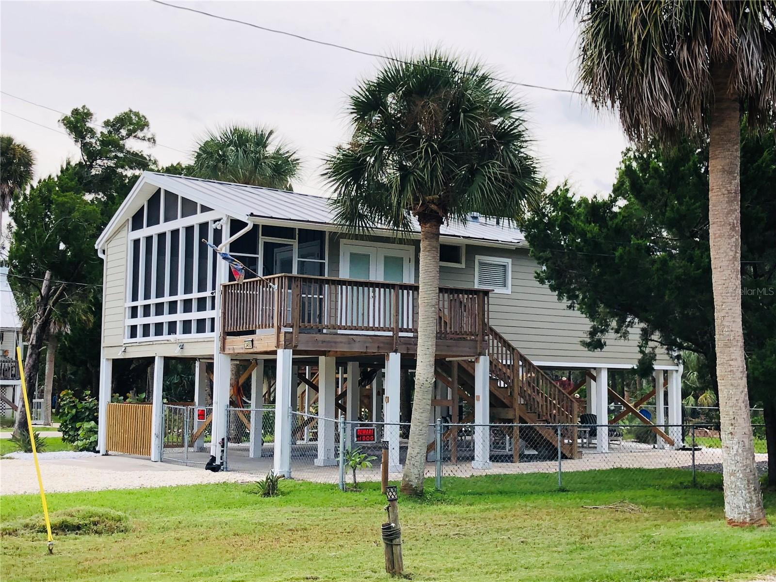 This Island 2 bedroom, 1 bathroom home is nestled in beautiful Pine Island. This home will give you total peace of mind with a long lasting metal roof, newer hurricane rated windows, new plumbing, new electric, new water heater, new a/c, and a new washer and dryer. This home showcases high cathedral ceilings with wood beams throughout the living areas. This kitchen offers a refrigerator, microwave, and stove. It features bright cabinets and dark quartz countertops. Both bedrooms have vaulted ceilings and ceiling fans and the full bathroom features a walk in shower, Outside, you will find relaxation and tranquility, whether you are entertaining your family and friends in your fully fenced yard or pulling up a chair around your fire pit. This Island oasis is a short walk to the beach. In less than 60 seconds, you can be barefoot walking in the sand and staring out into the Gulf for those Gulf Coast sunsets you dream about. This location is truly storybook! This home even has amazing rental opportunities. This home will have the opportunity to come COMPLETELY FURNISHED and turnkey. Close to amazing local restaurants, shopping, fishing, and private boat ramps for residents, this home has it all. Welcome home