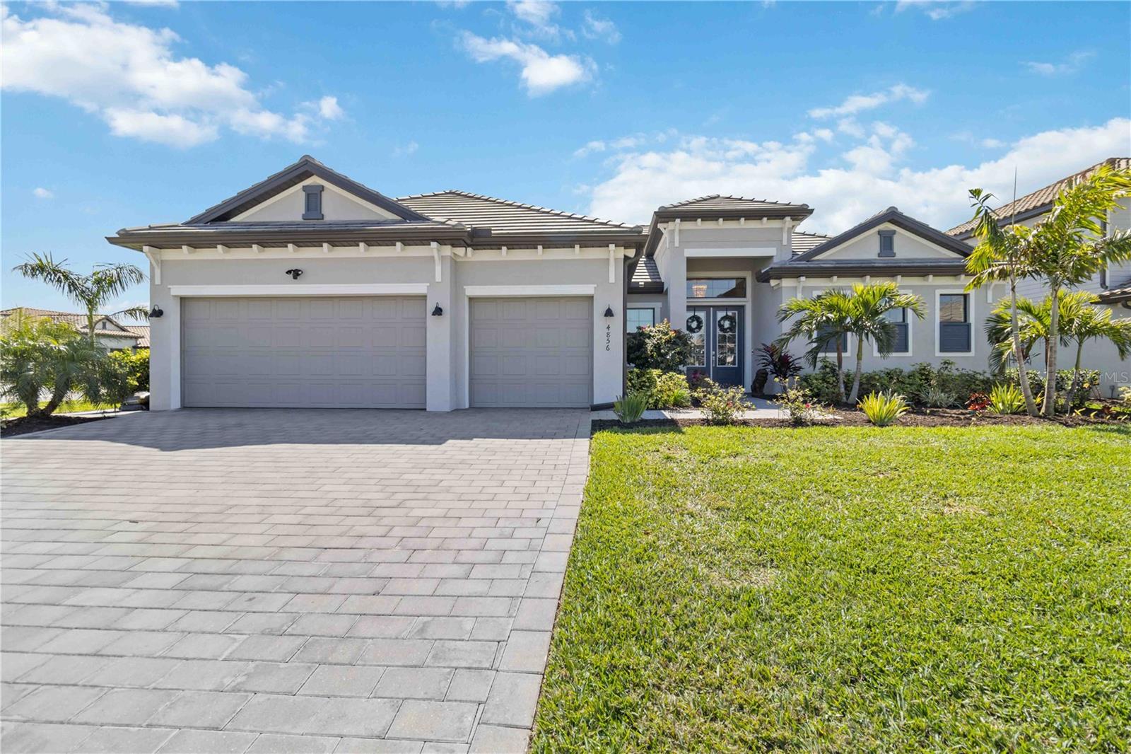 Experience luxury and tranquility in this stunning 3-bedroom, 3-bathroom home! The heart of the home features a spacious kitchen with a large quartz island, perfect for entertaining. The living area boasts a ledgestone accent wall, an electric fireplace, and floating shelves, creating a warm and inviting ambiance. Step outside to your private tropical oasis, where lush tropical foliage surrounds a custom pool with a waterfall, glass bowls, and a sunledge. Relax in the raised spa, which overflows seamlessly into the pool, all set on a travertine pool deck for a true resort-style experience. This exceptional home also includes a spacious three-car garage, offering ample storage and convenience. The community of Lorraine Lakes has resort-style amenities, including 2 pools, a splash pad, on-site restaurant with indoor and outdoor dining, state-of-the-art fitness center with sauna's in the men's and women's locker rooms, pickleball, tennis, indoor and outdoor basketball courts, Bocce ball courts, and volleyball courts. Events such as wine tastings, trivia nights, and themed events are regularly hosted. Located just minutes from beaches, dining, and entertainment
