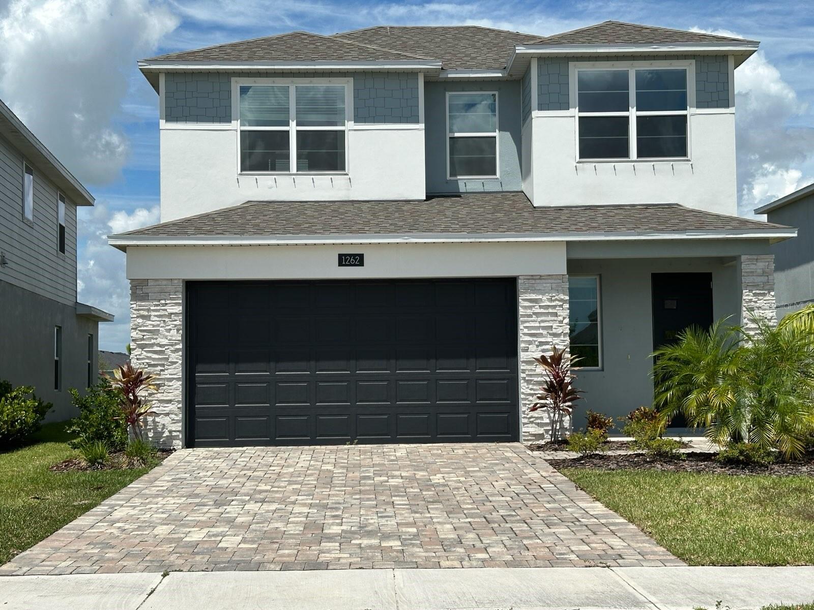 Under contract-accepting backup offers. This is truly a must-see! Fall in love with this stunning waterfront home featuring four bedrooms and three bathrooms, situated in the Gardens at Waterstone community. This home was used as sales center/model home so it's never been occupied. As you approach, the charming curb appeal is immediately striking, accentuated by a paver driveway, stone details, and a welcoming covered front porch. Upon entering, you will be greeted by high ceilings, tile flooring throughout the main living areas, and a picturesque view of the pond. The kitchen is a culinary delight, equipped with stainless steel appliances, a flat cooktop, built-in oven, built-in microwave, pantry, and a breakfast bar perfect for casual dining. The dining room is conveniently located directly adjacent to the kitchen, making it effortless to host dinner parties. You can relax in the living room or step onto the covered patio to enjoy the fresh air while gazing out at the serene pond. The primary bedroom, located on the ground floor, features an ensuite bathroom and a spacious walk-in closet. There is also an additional guest bedroom, full bathroom and laundry room on the ground floor, for your convenience. As you ascend to the second floor, you'll discover a loft area that provides the extra space you desire. This level includes two ample sized bedrooms, a full bathroom, and a cozy study or den area. This contemporary, split-bedroom, floor plan designs ensures functional spaces. Notably, there are no rear neighbors and no CDD fees. The Gardens at Waterstone community is ideally located 30 minutes from the beaches and offers convenient access to I-95. Don’t miss this opportunity!