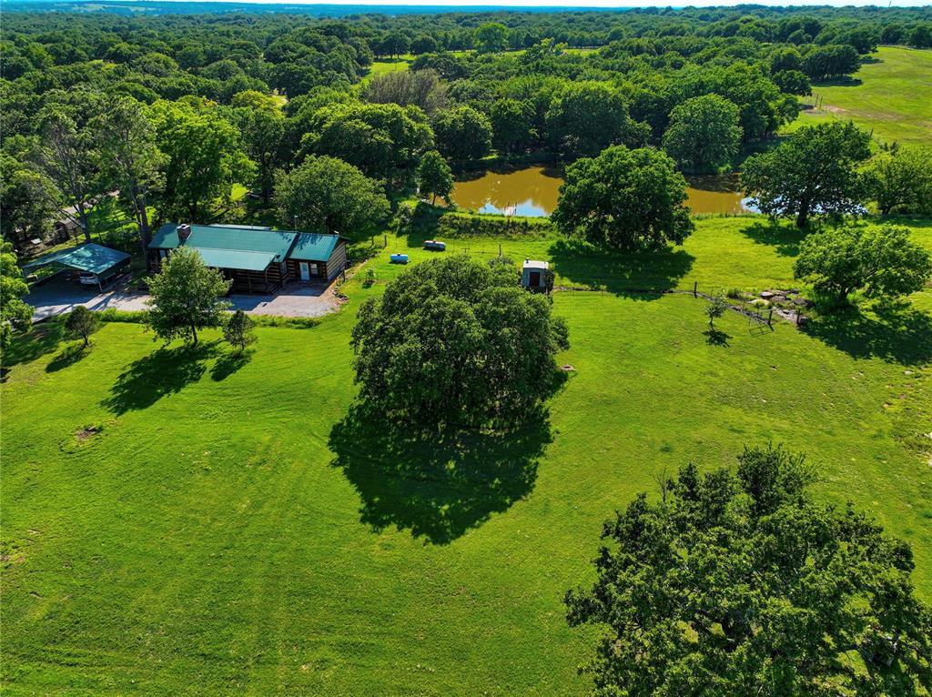 View of main cabin with large pond and above ground storm shelter in view.