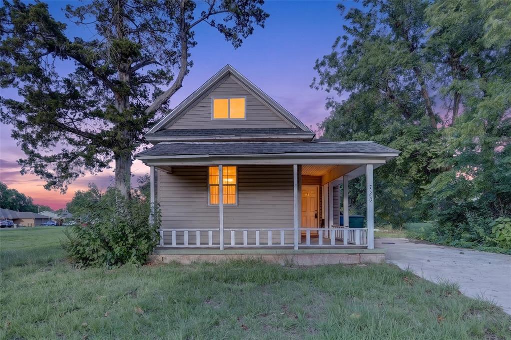 View of front of home featuring a shingled roof, covered porch, and driveway