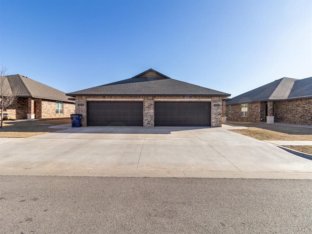 Brick exterior featuring dark garage doors, stone accents, and a gabled roofline