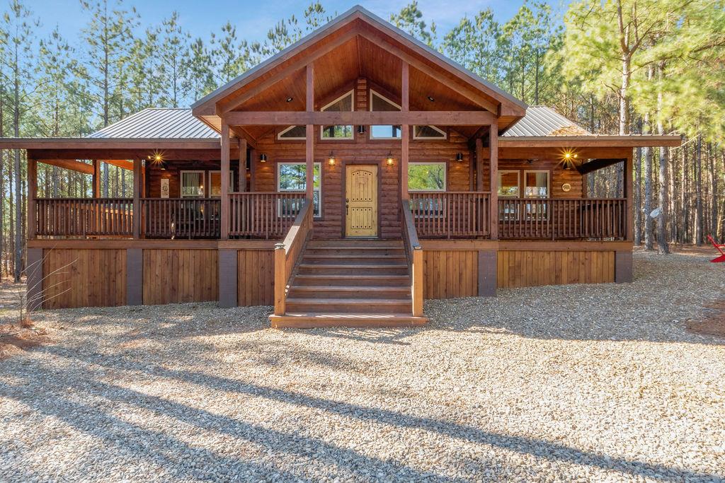 Chalet / cabin with a metal roof, log veneer siding, and covered porch
