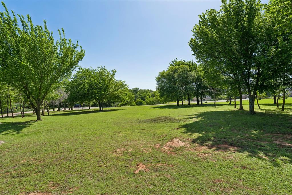 Expansive green space featuring mature deciduous trees and natural landscaping