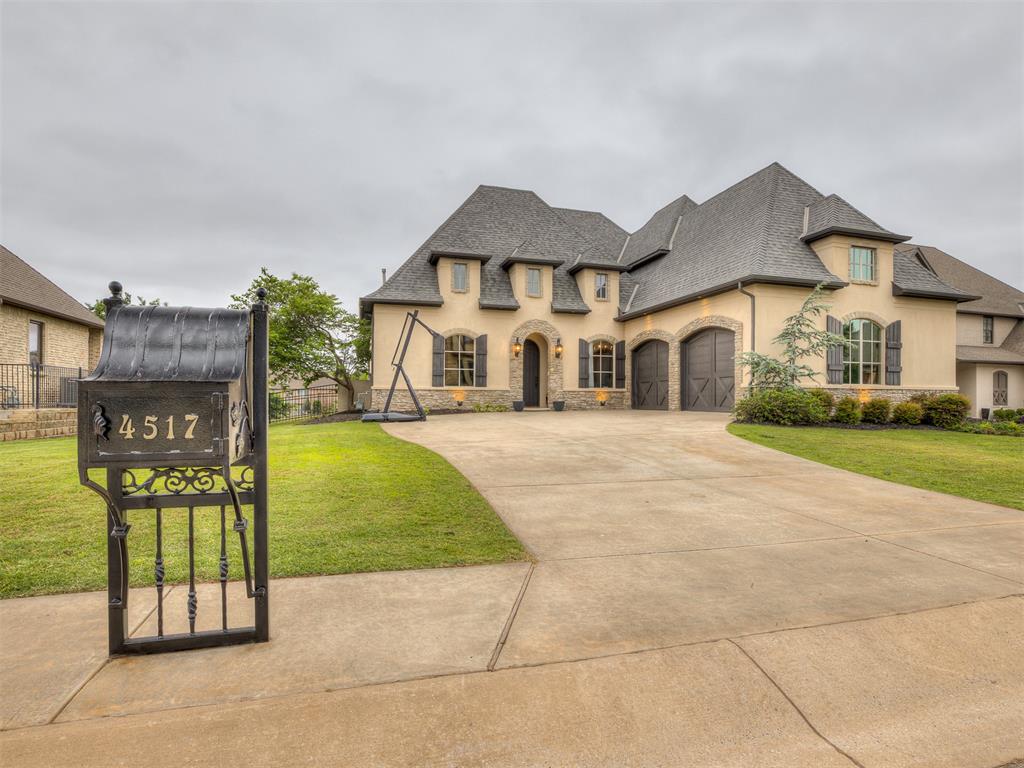 Stone and stucco exterior residence featuring a multi-car garage, mature landscaping, and a paved driveway