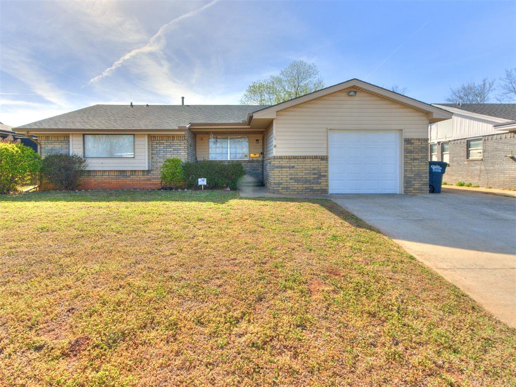 Ranch-style house featuring concrete driveway, brick siding, a garage, and a front yard