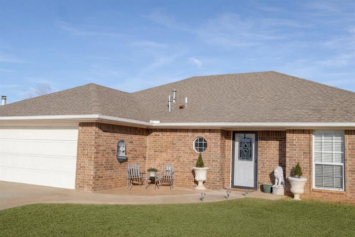 View of front facade with roof with shingles, an attached garage, brick siding, a front yard, and concrete driveway