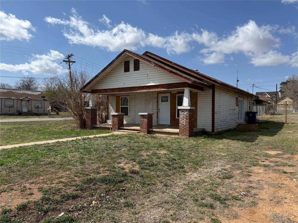 View of front facade with covered porch and a front lawn
