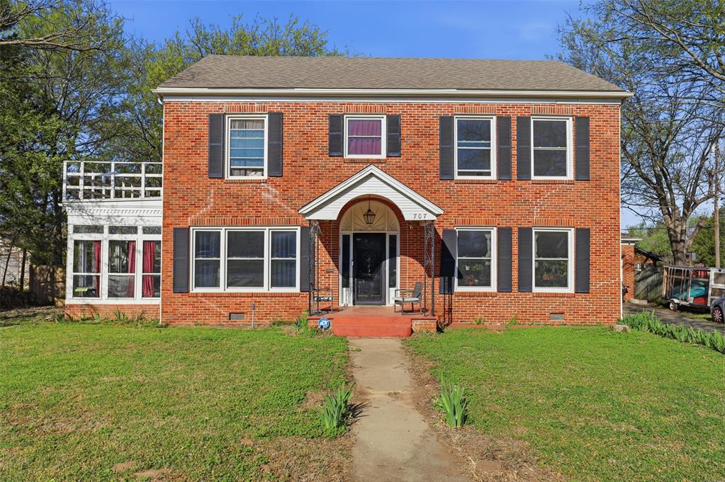 Colonial home featuring crawl space, a front lawn, and brick siding