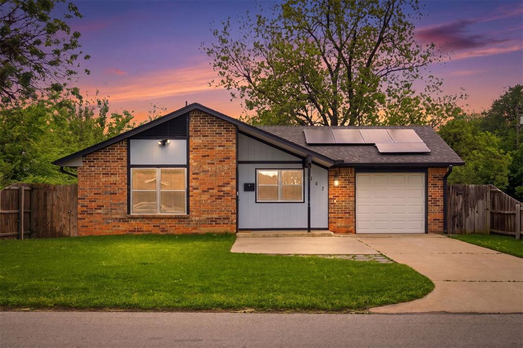 The property features a brick and siding exterior, a front yard with a lawn, and a paved driveway leading to a garage