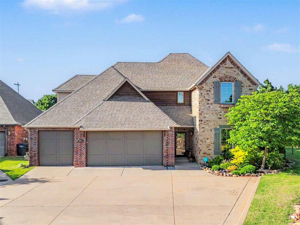 Two-story residence featuring a stone and brick facade, a multi-gabled roofline, and a three-car garage