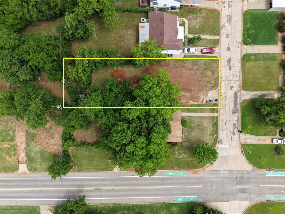 Expansive undeveloped parcel featuring mature trees, a partially cleared section, and roadside frontage