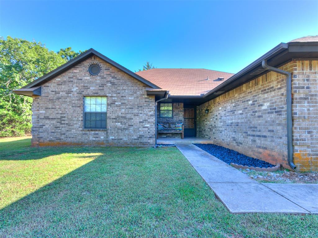 Property entrance featuring a lawn and brick siding