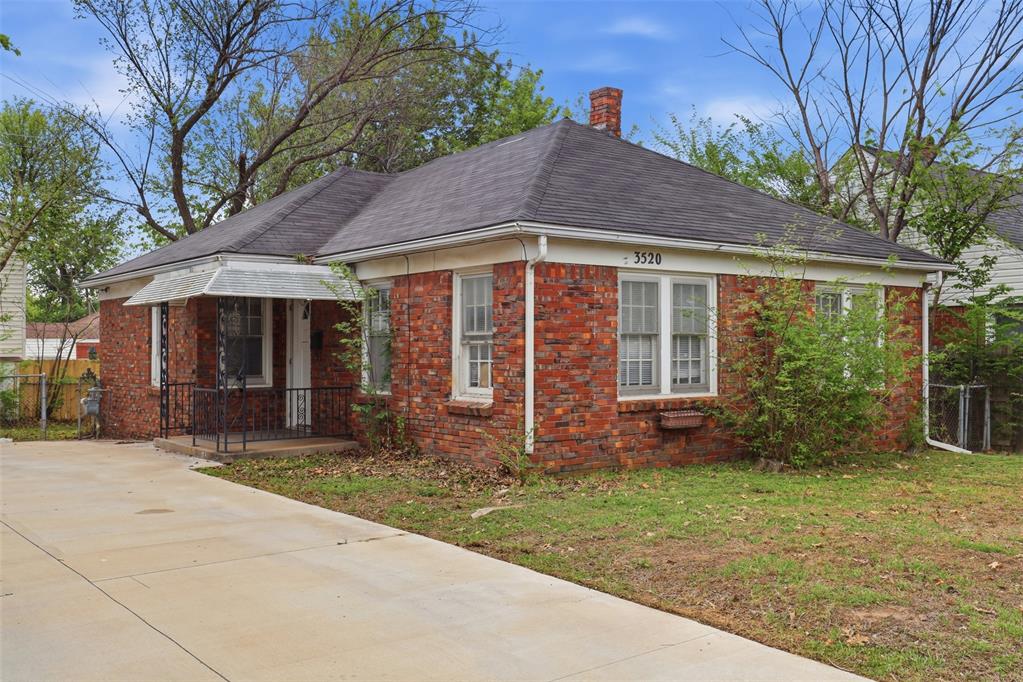 View of side of home with brick siding, a chimney, a shingled roof, and covered porch
