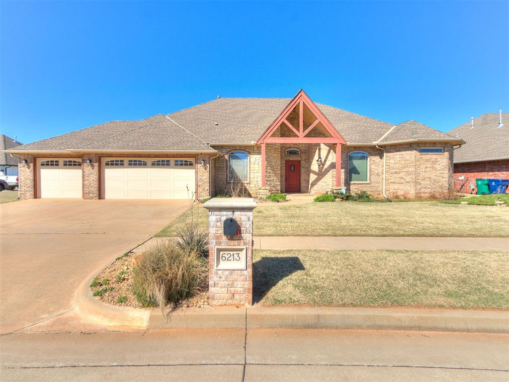 View of front of house featuring an attached garage, roof with shingles, concrete driveway, a front yard, and brick siding
