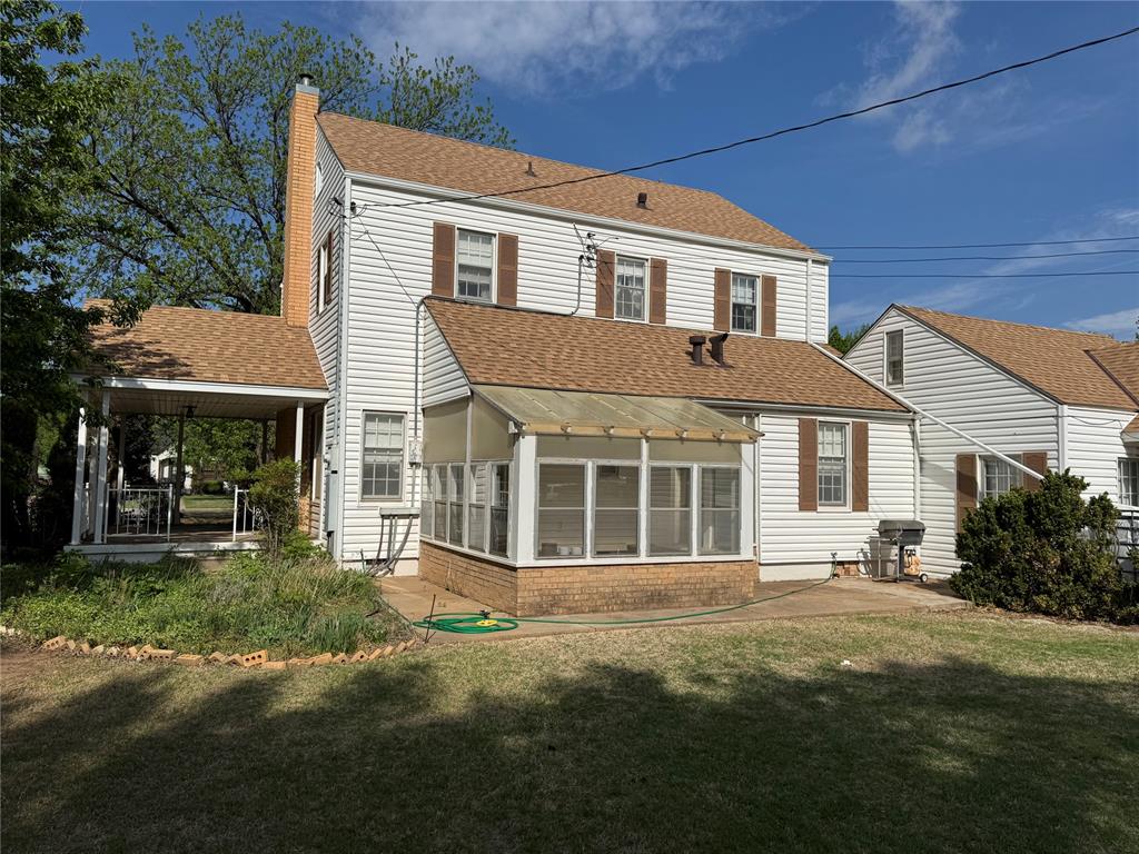 The property features white siding, a brown shingled roof, and a brick chimney