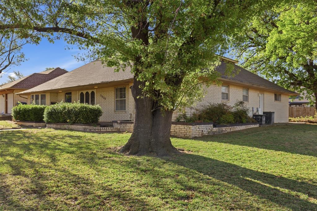 View of front of property featuring a front lawn, roof with shingles, and brick siding