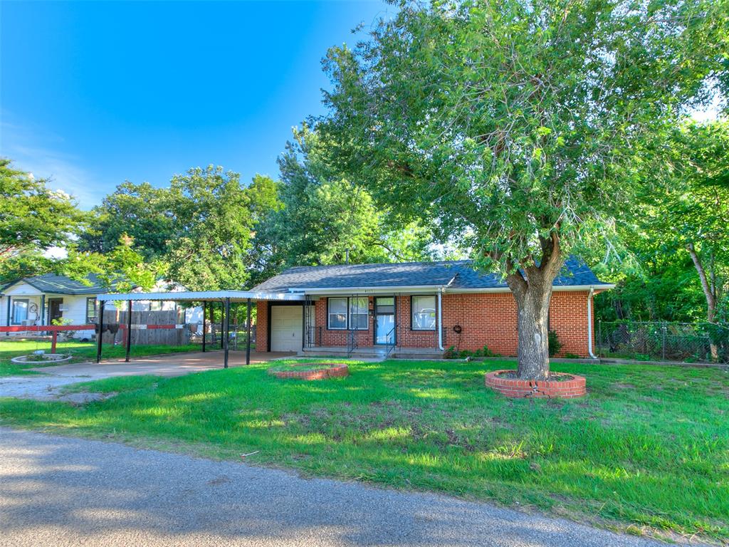 View of front of home featuring a carport, brick siding, driveway, and a garage