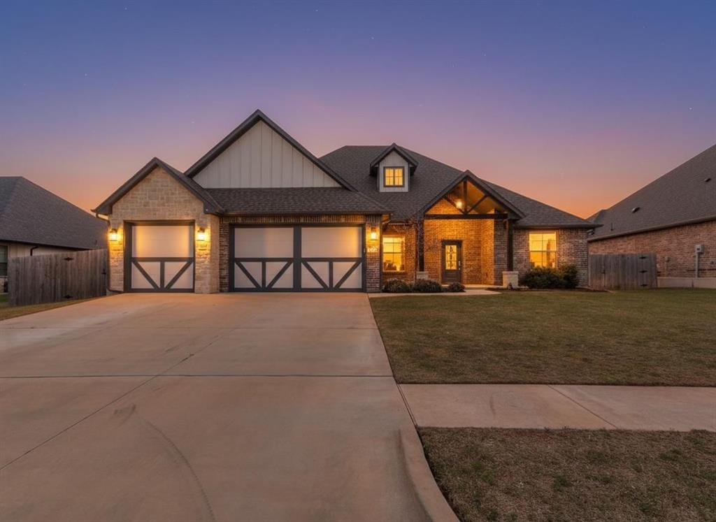 View of front of house featuring an attached garage, driveway, board and batten siding, stone siding, and covered porch