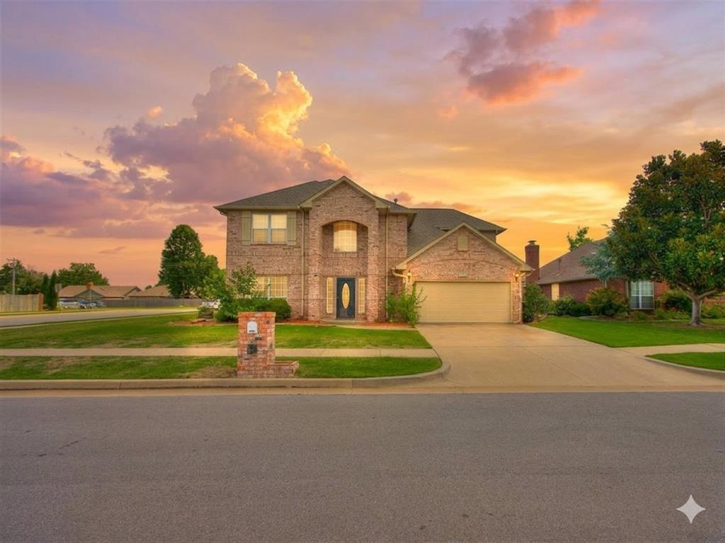 Traditional-style house featuring a front yard, an attached garage, concrete driveway, and brick siding