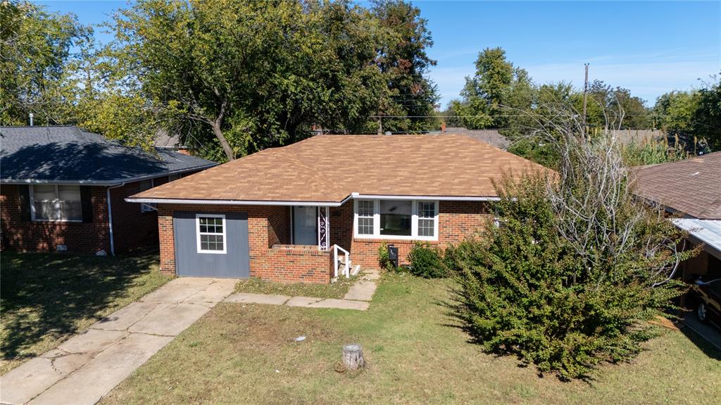 View of front of property featuring a front lawn, brick siding, and roof with shingles