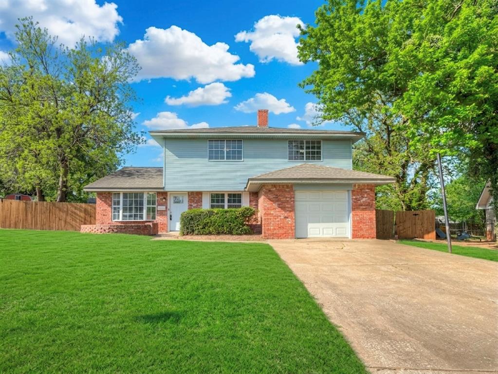 Traditional-style house with concrete driveway, a chimney, brick siding, and a garage