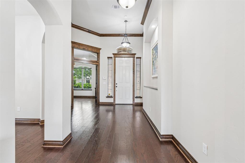 Formal entry featuring dark wood-finish flooring, white walls, and dark wood trim