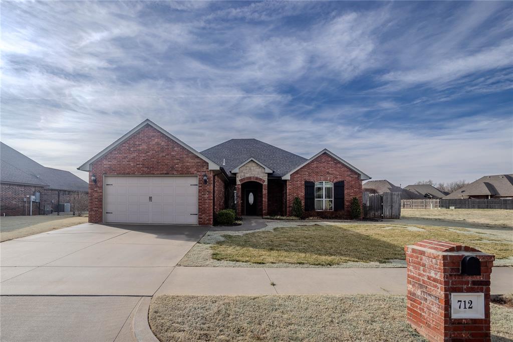 View of front of property with brick siding, an attached garage, driveway, and a shingled roof