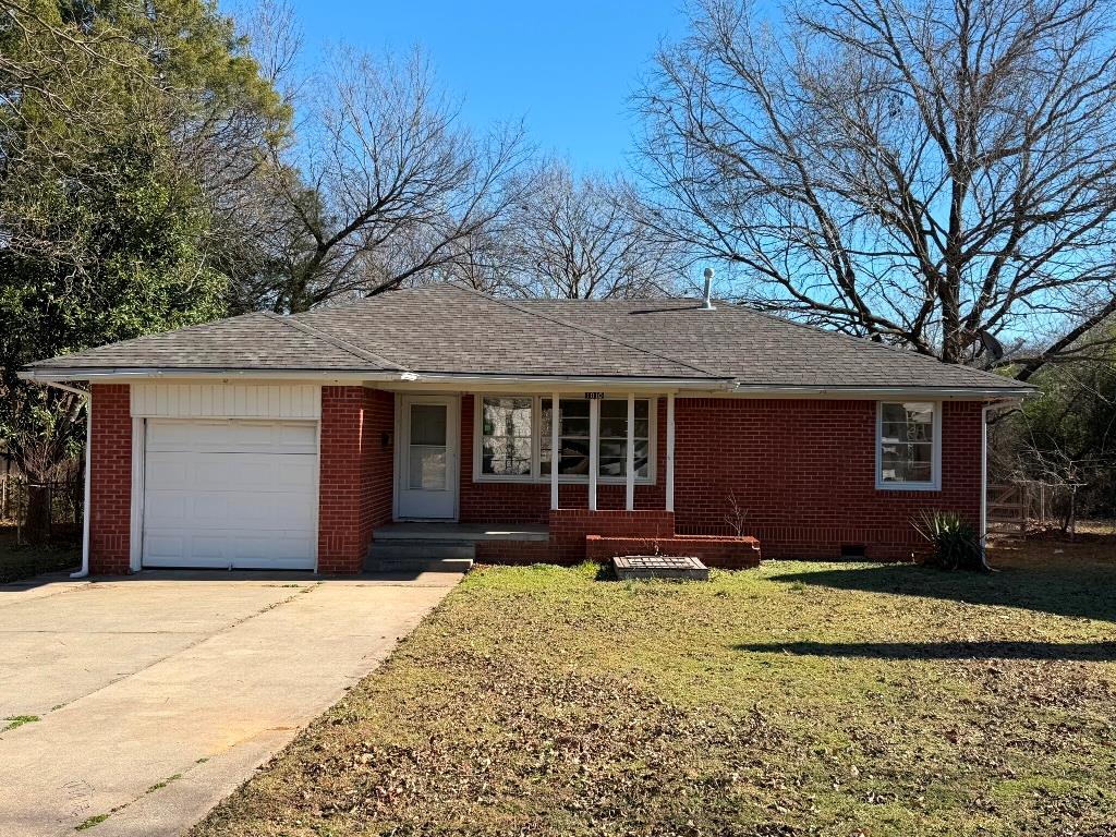 Ranch-style home featuring driveway, brick siding, a front yard, and roof with shingles