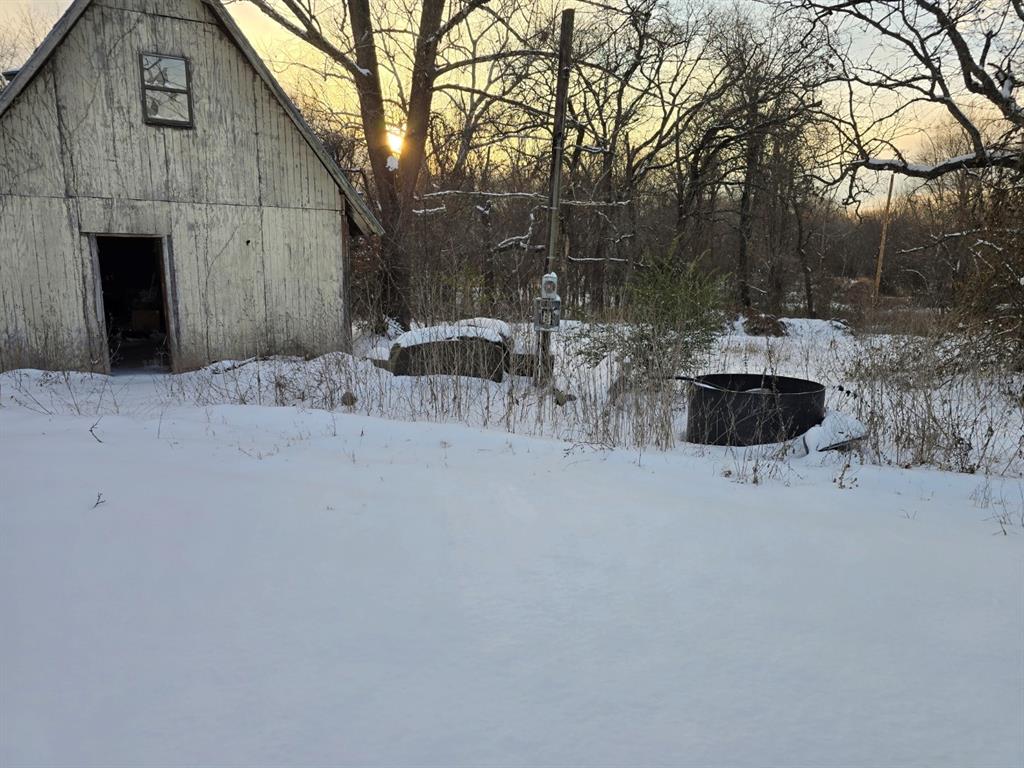 Yard covered in snow with a barn and an outdoor structure