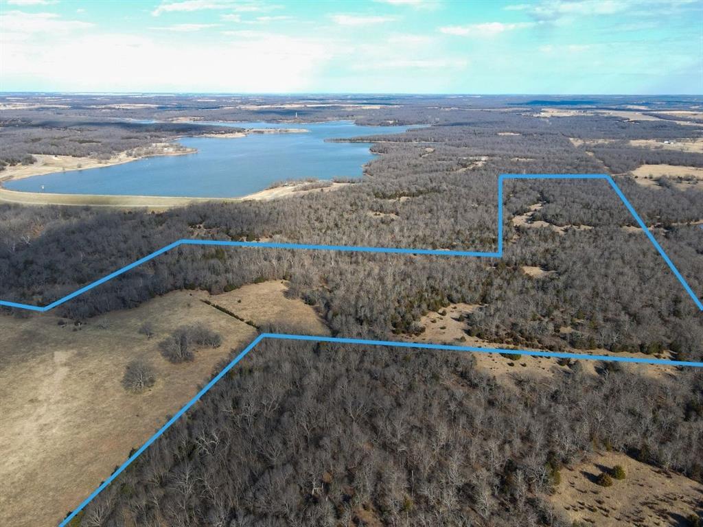 Aerial view of property and surrounding area with a large body of water and property boundaries highlighted