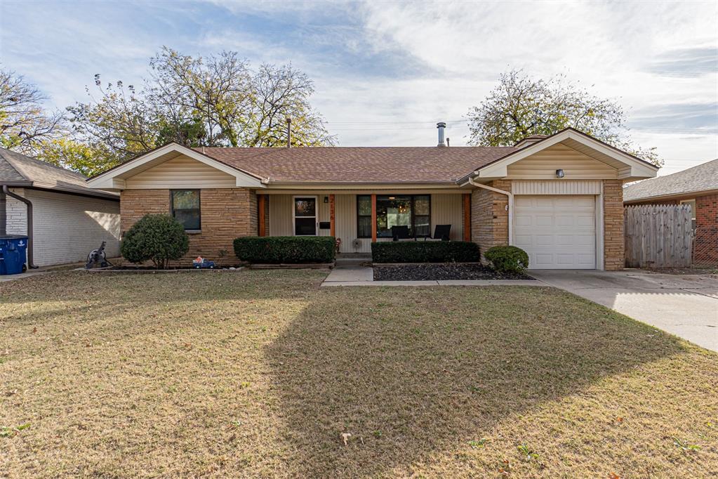 Single story home with a porch, roof with shingles, brick siding, a garage, and driveway