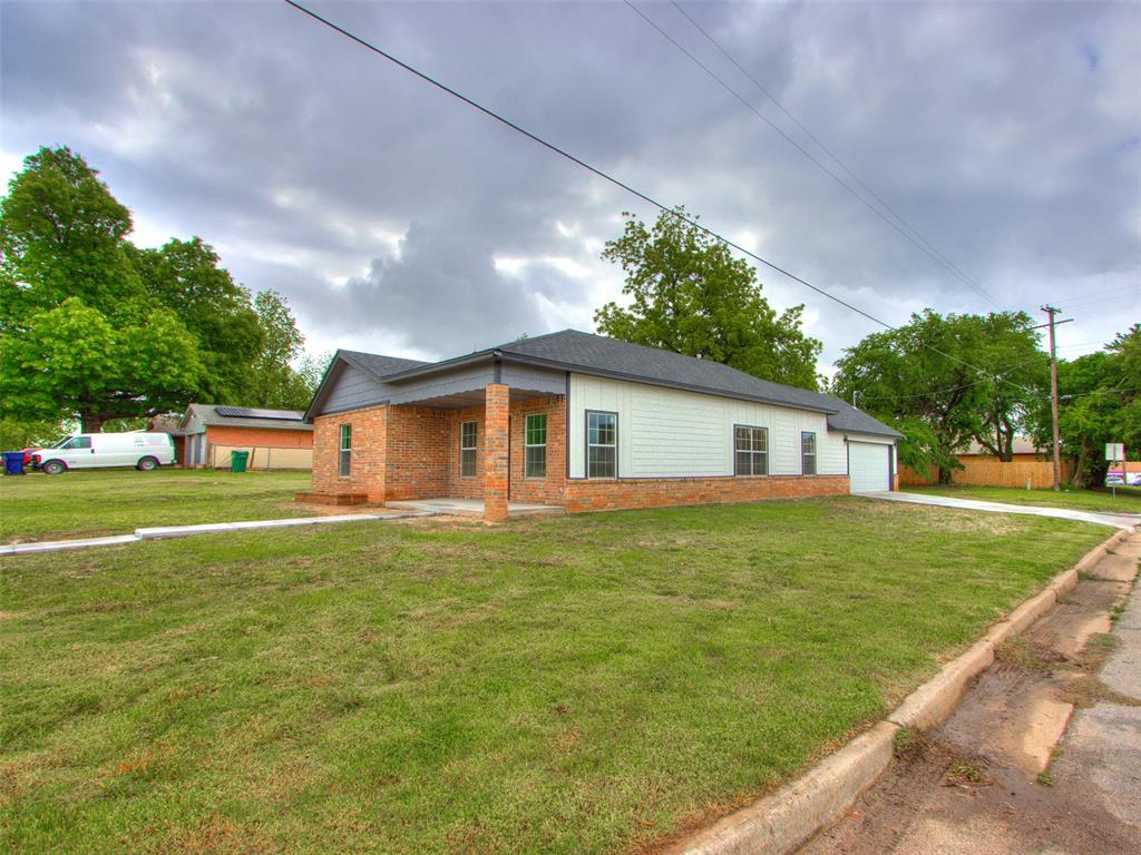Single story home with a front yard, a patio, a garage, and brick siding